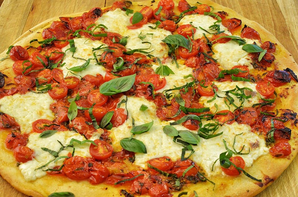 izbliza prikaz svjeze pecene pizze sa paradajzom i bosiljkom